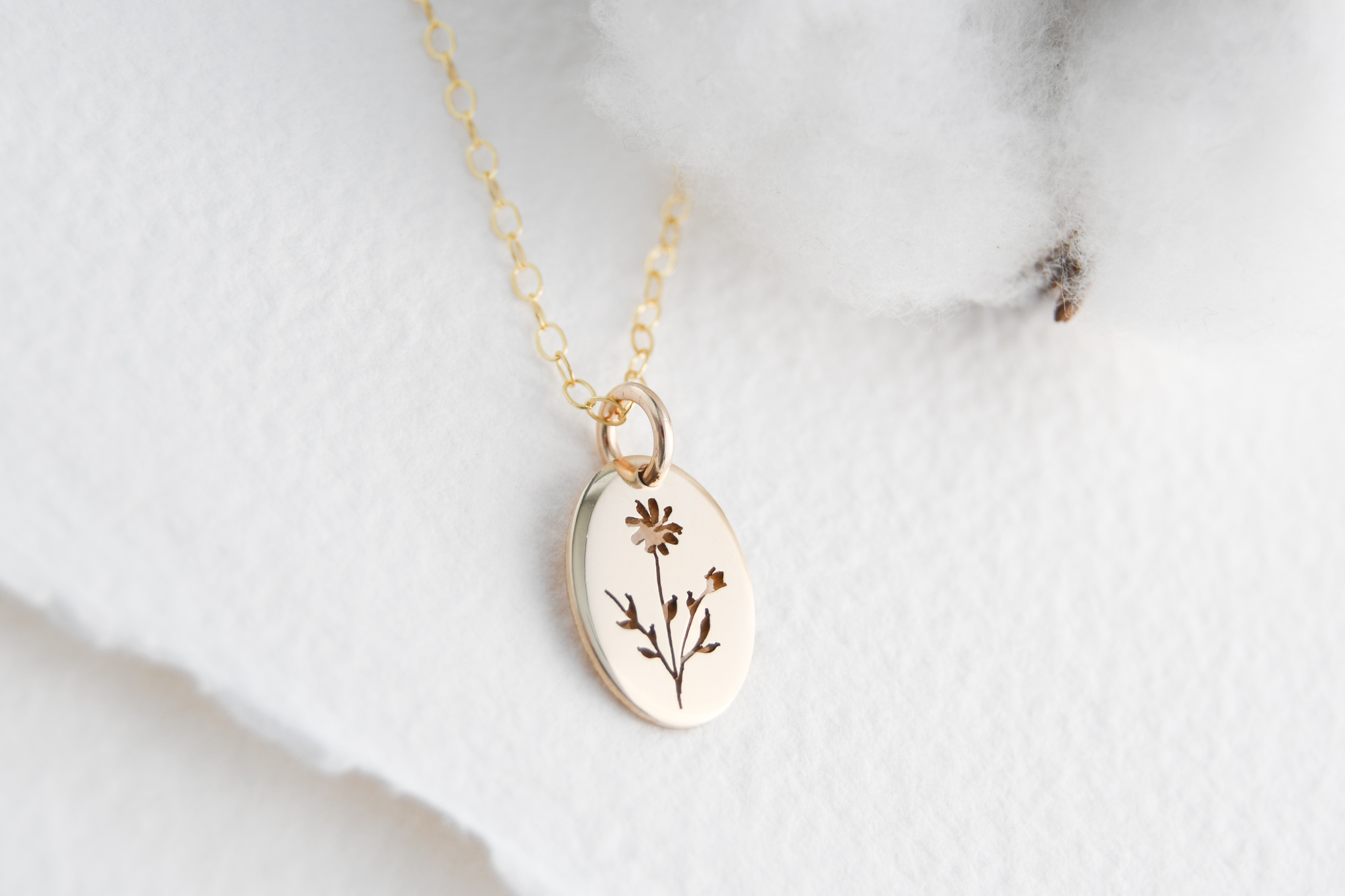 Gold filled oval pendant with a flea bane flower hand cut on the pendant