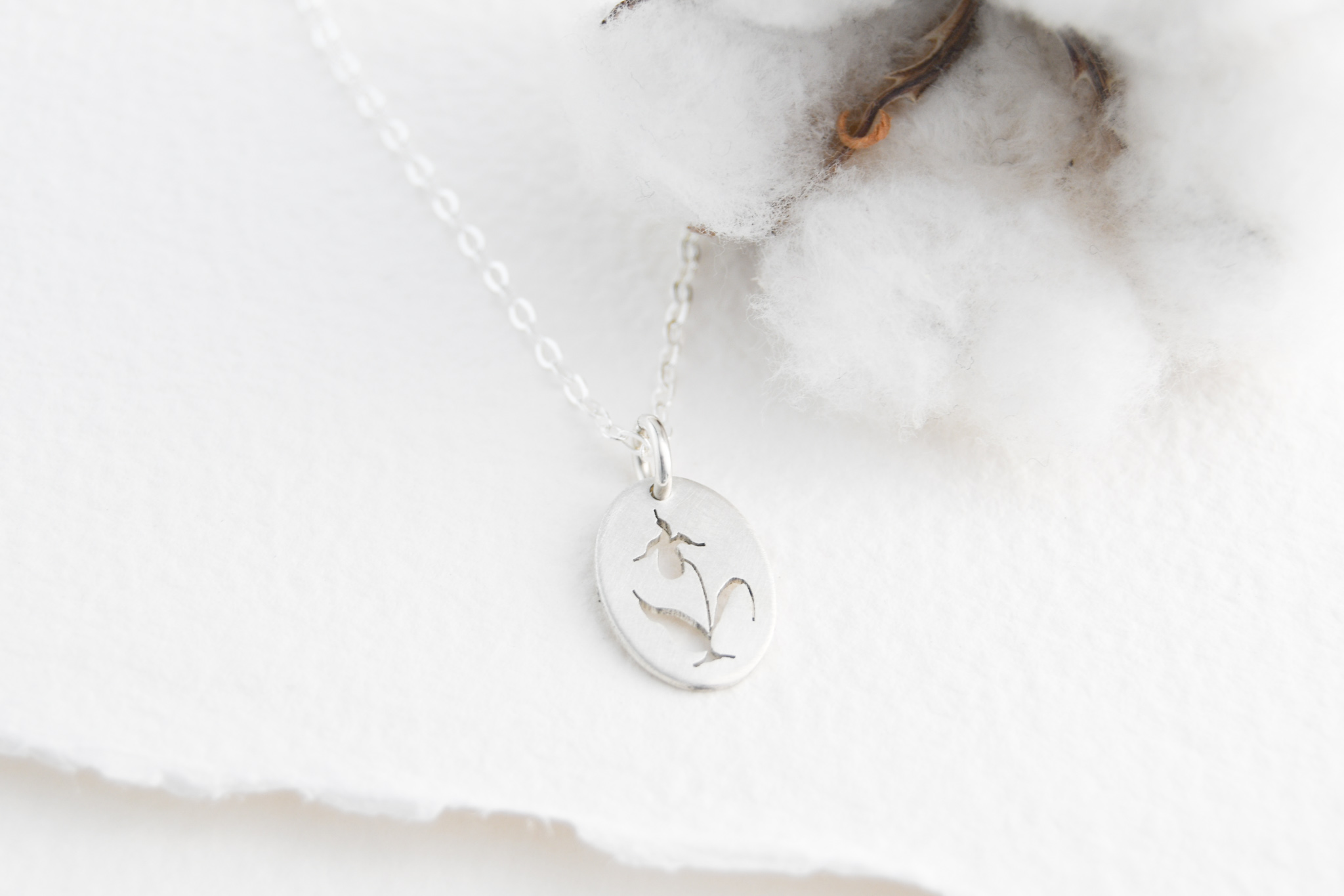 Sterling silver oval pendant with a hand cut lady slipper orchid cut out of the pendant.