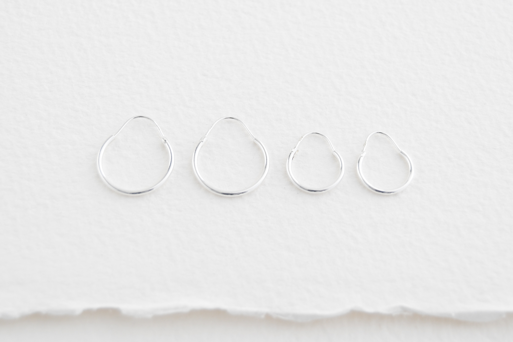 Sterling silver sleeper hoop style earrings. Two sizes medium on the left and small on the right.