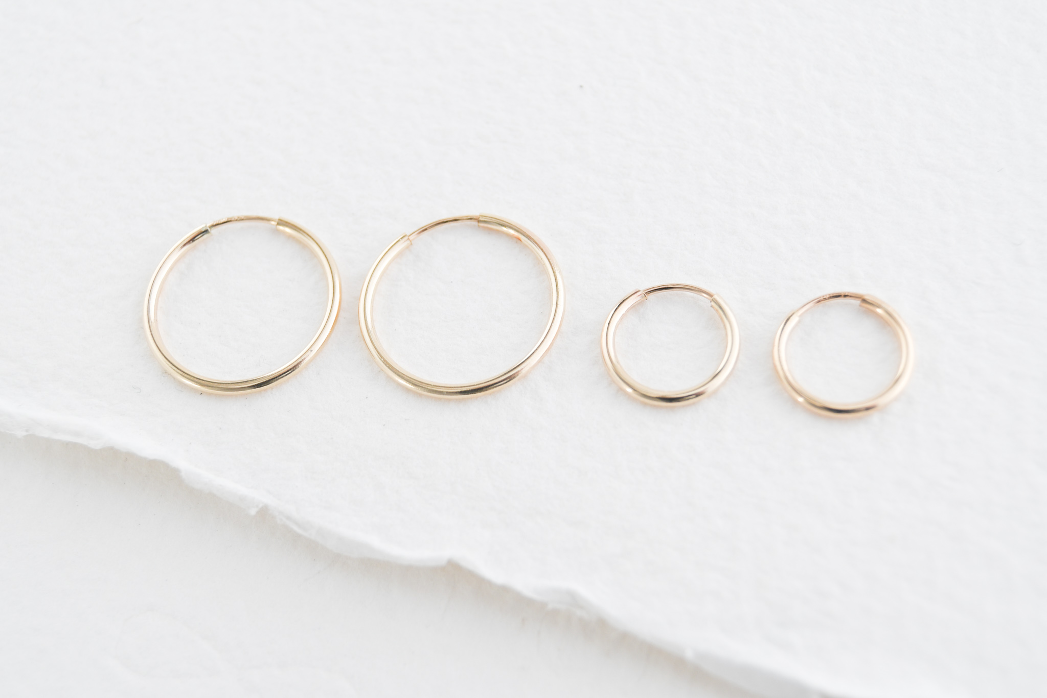 Two sizes of gold filled sleeper style hoops. Left size medium hoops, right side small hoops.